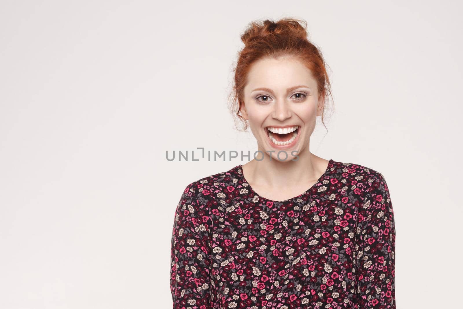 The attractive redhead woman with perfect clean skin smiling at camera with happy and joyful. Isolated studio shot on gray background.