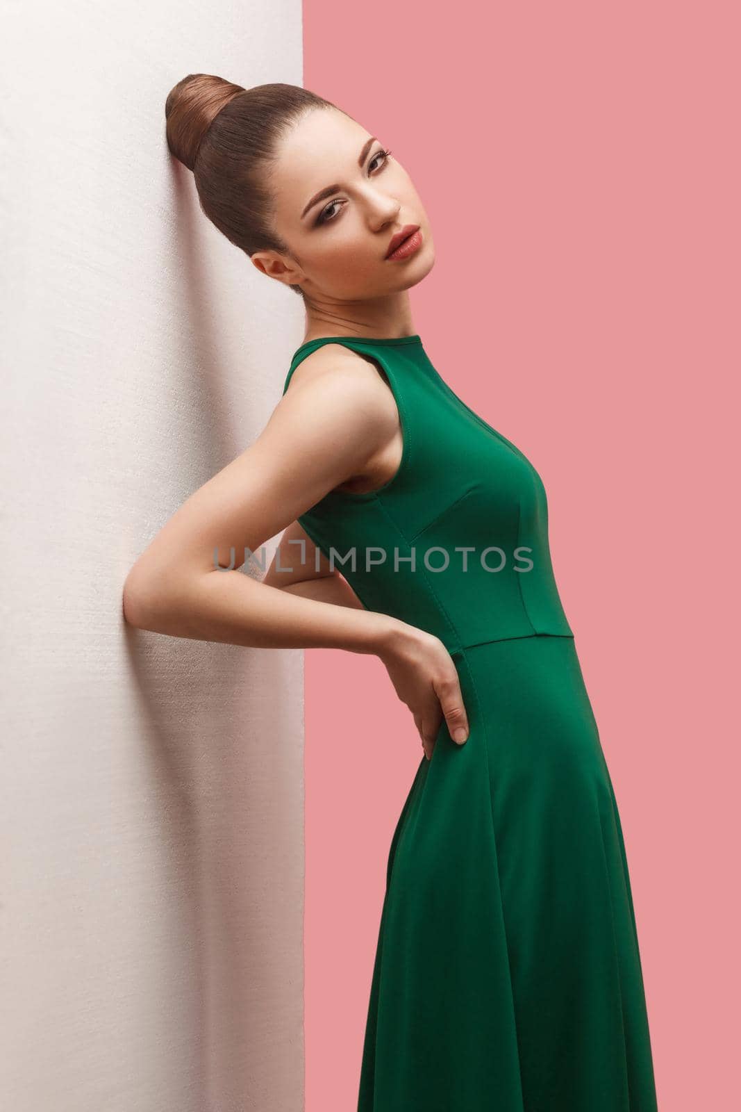 Beauty concept of young beautiful female model in green dress on pink background. by Khosro1