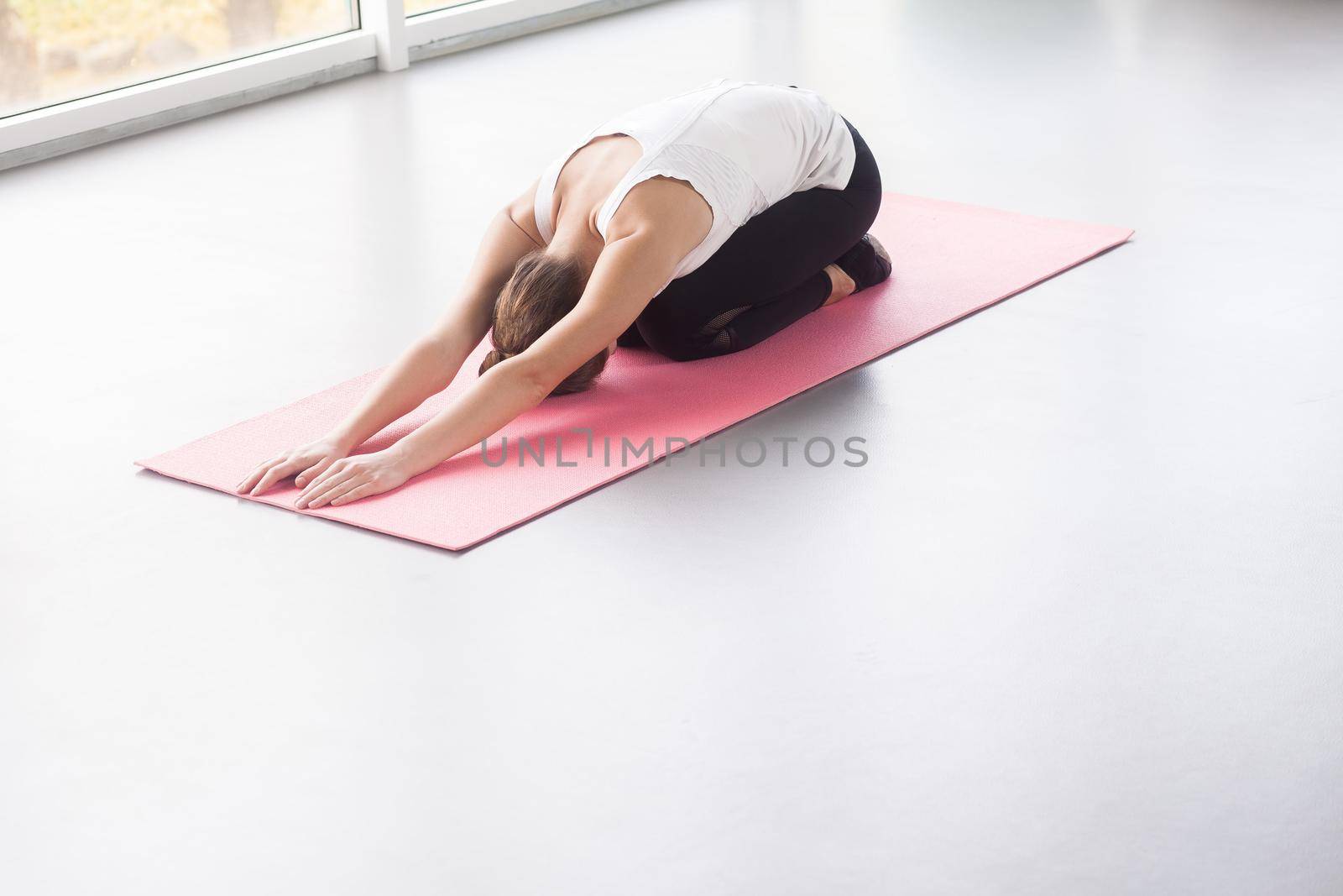 Young woman doing child’s posture. Studio shot