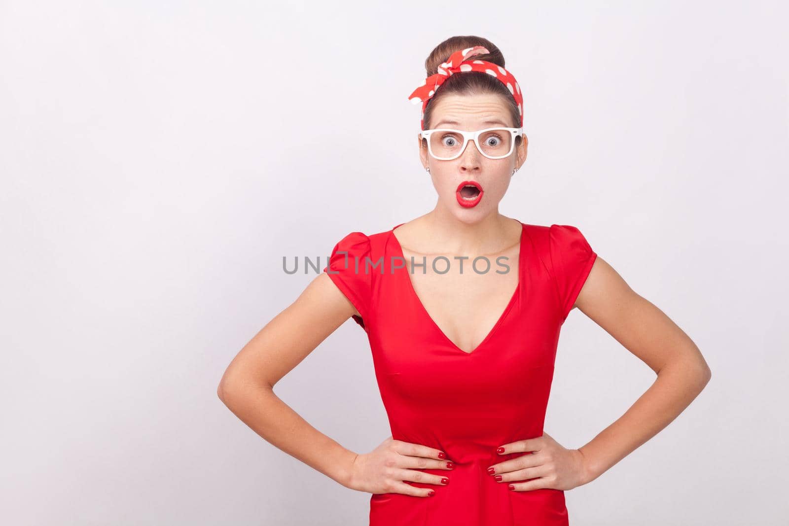 Expressive surprised woman, open mouth with shock, looking at camera. Indoor, studio shot, isolated on gray background