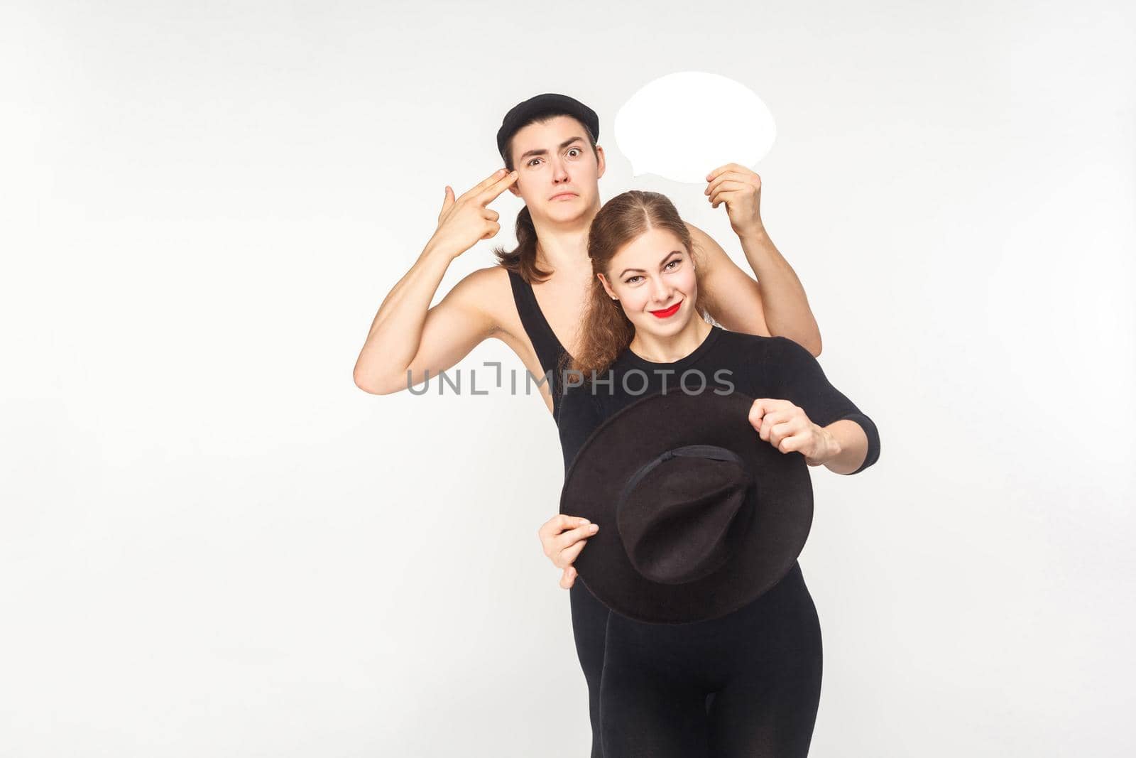 Traffic rules. Couple driving a car, man showing gun sign. Studio shot, isolated on white background