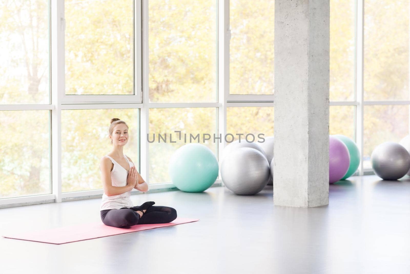 Bound Angle, lotus posture. Woman doing yoga, looking at camera. Studio shot
