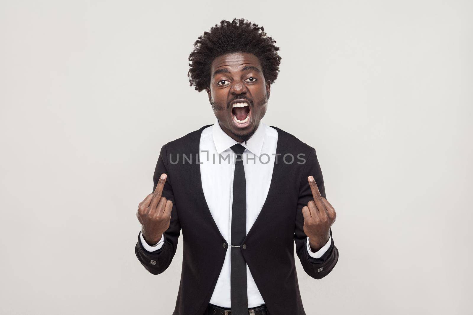 Fuck sign. African man pointing fingers at camera. Studio shot