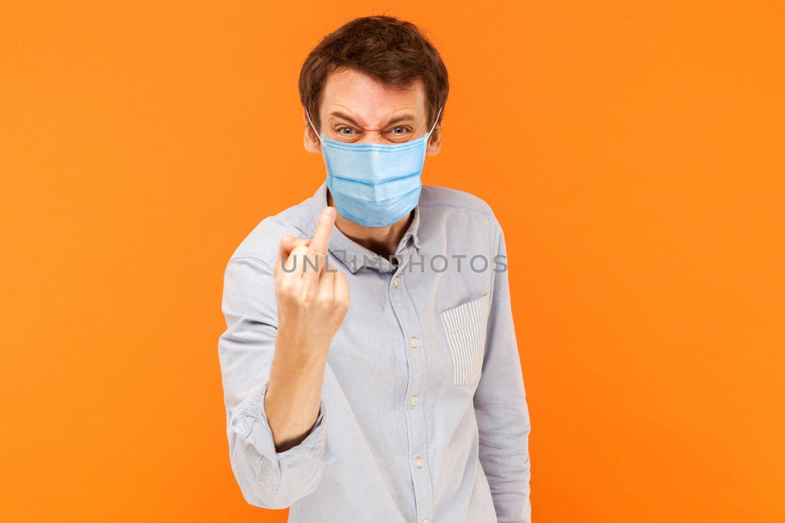 man with surgical medical mask standing looking at camera with middle finger and aggressive face. by Khosro1