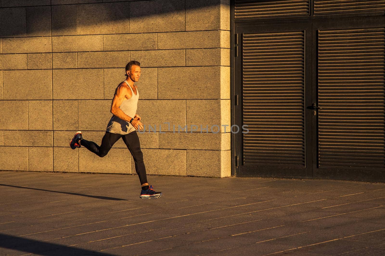 Aged sportsman running on country road, healthy inspirational fitness lifestyle, sport motivation speed interval training. Runner jogging training and doing workout exercising power walking outdoors in city.