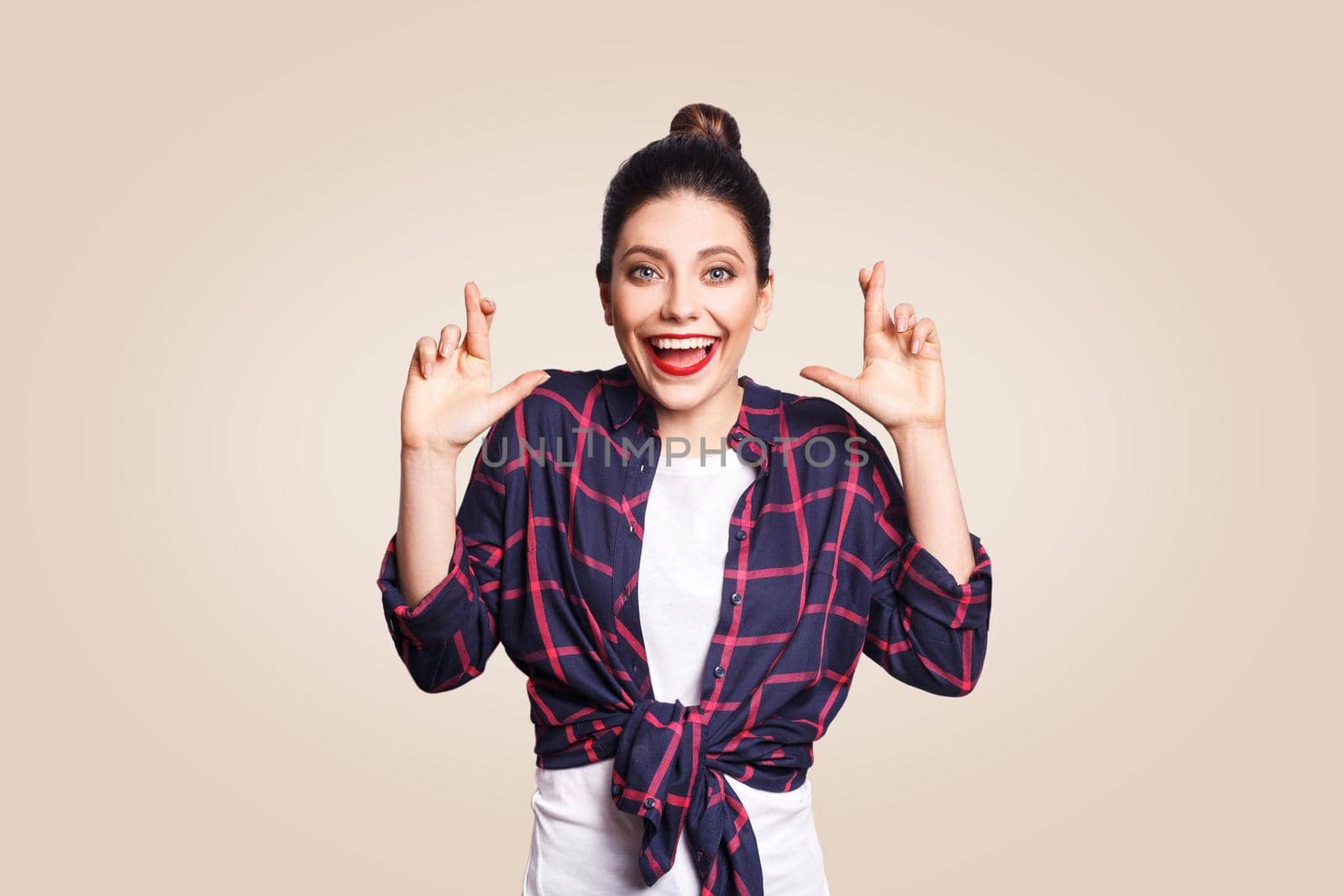 Portrait of beautiful girl in casual style looking at camera with liar pose laughing. studio shot on beige background.