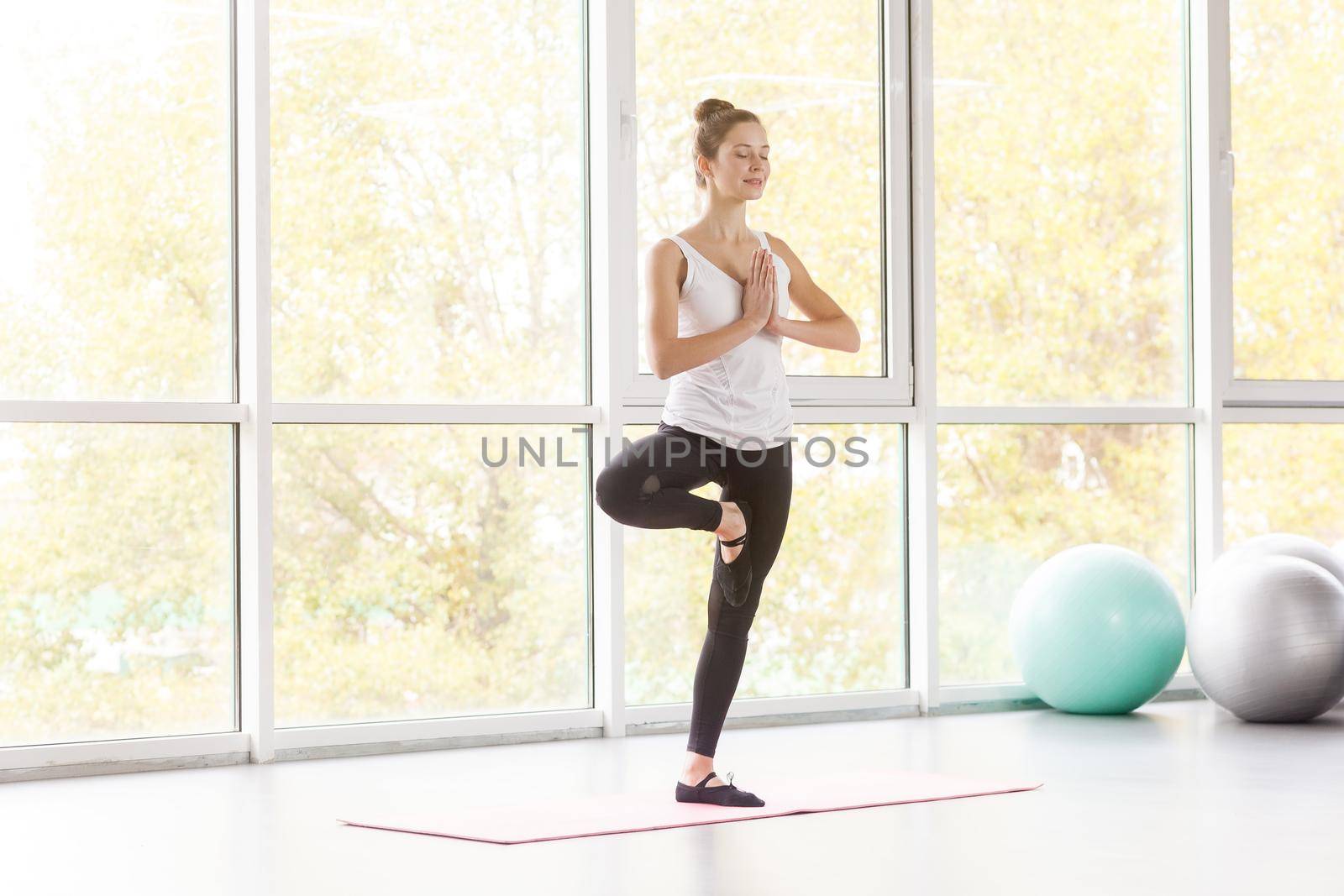 Tree posture. Woamn balancing on one leg and doing yoga. Studio shot