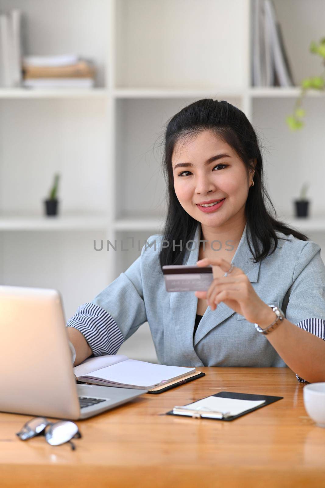 Portrait young asian woman holing credit card and using computer laptop for payment online. by prathanchorruangsak