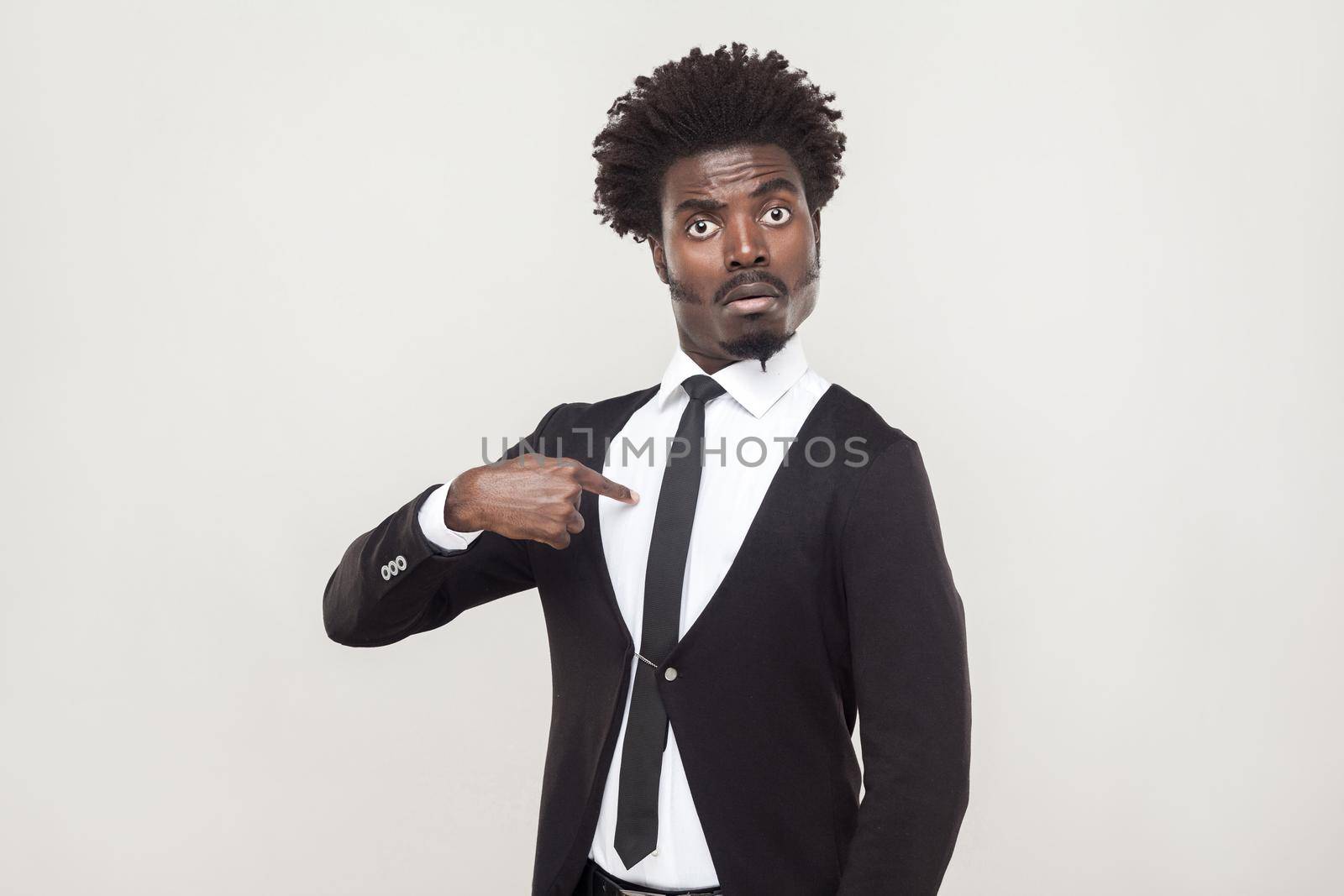 Amazement aloof afro man looking at camera and pointing finger himself. Studio shot, gray background