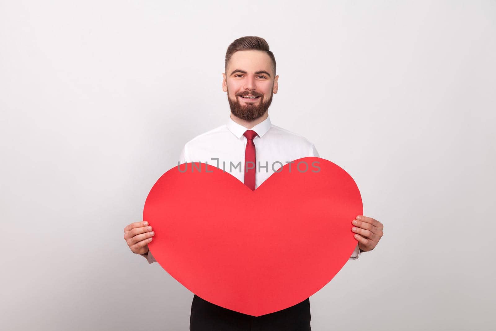 Valentines day. Energy businessman toothy smiling, holding big red heart by Khosro1
