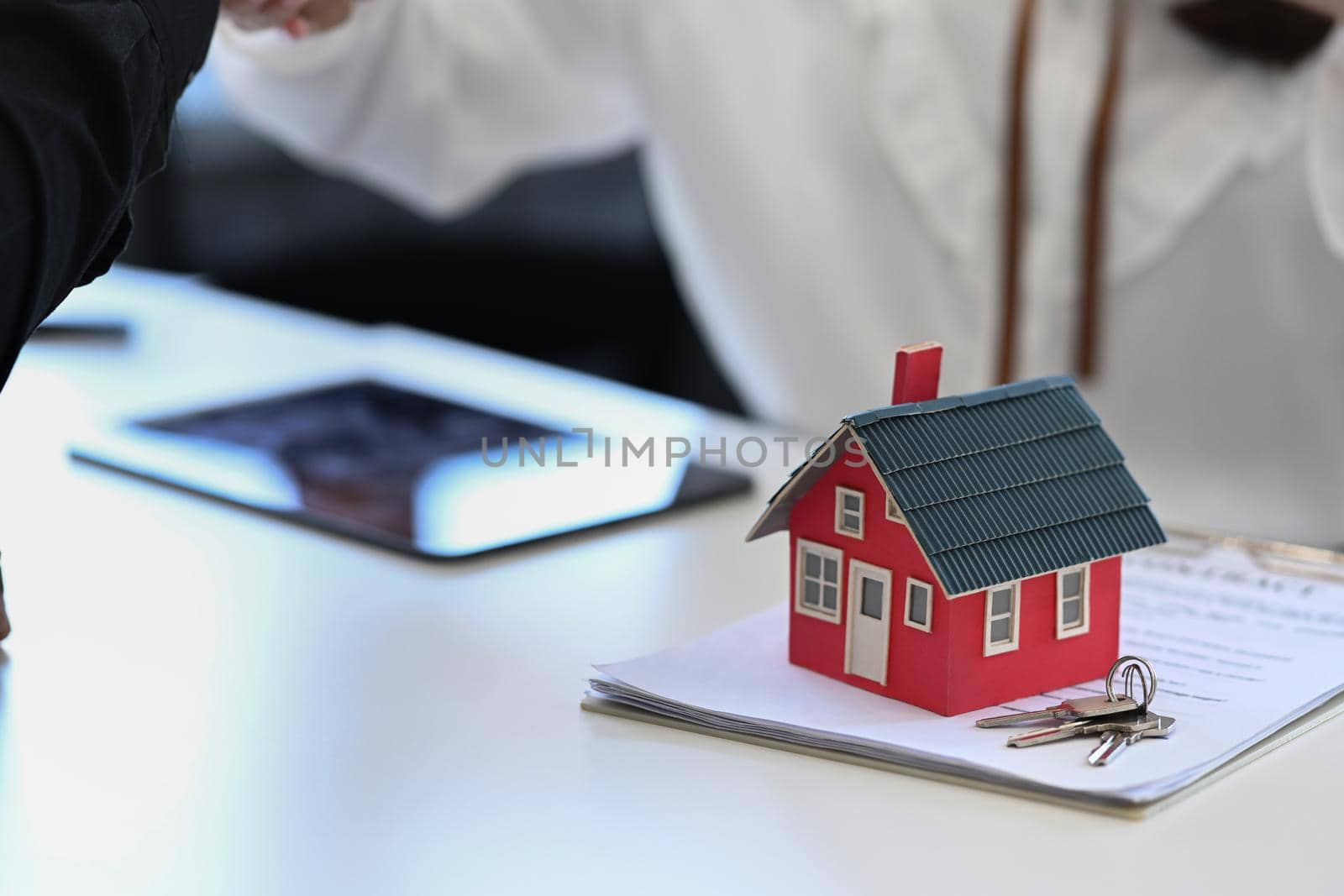 House model, keys and contract document on white table. by prathanchorruangsak