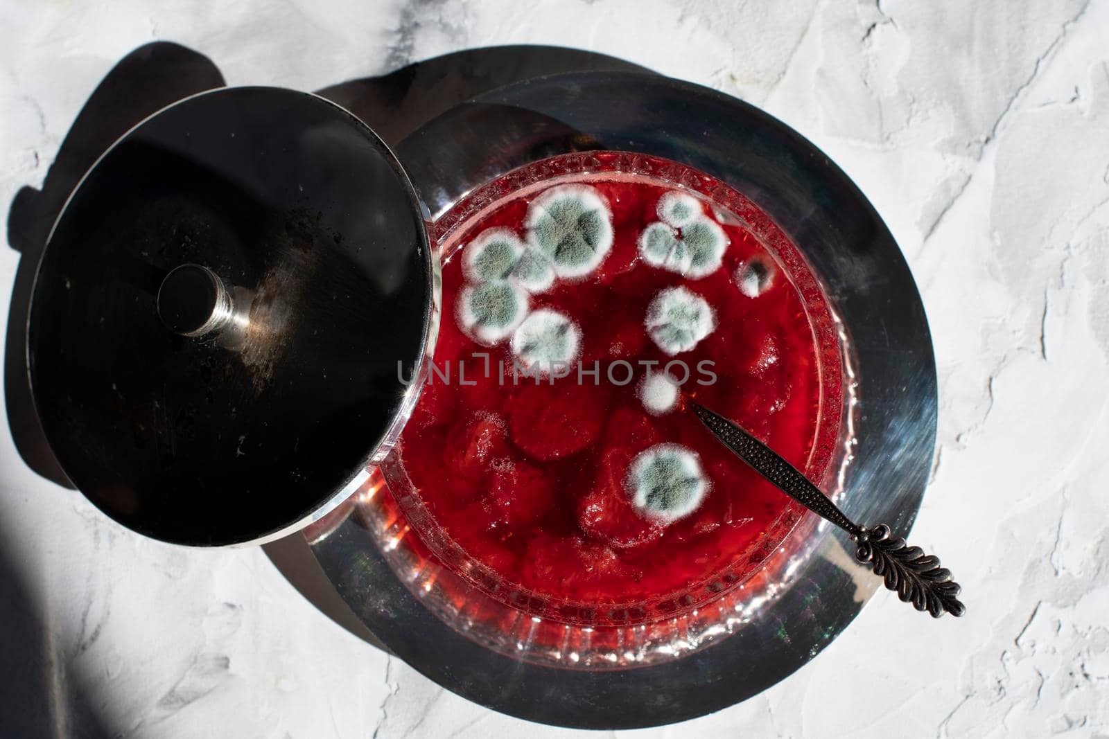 blue mold on strawberry jam, violation of cooking technology, health hazard, spoiled product, beautiful blue spots on a red background. High quality photo