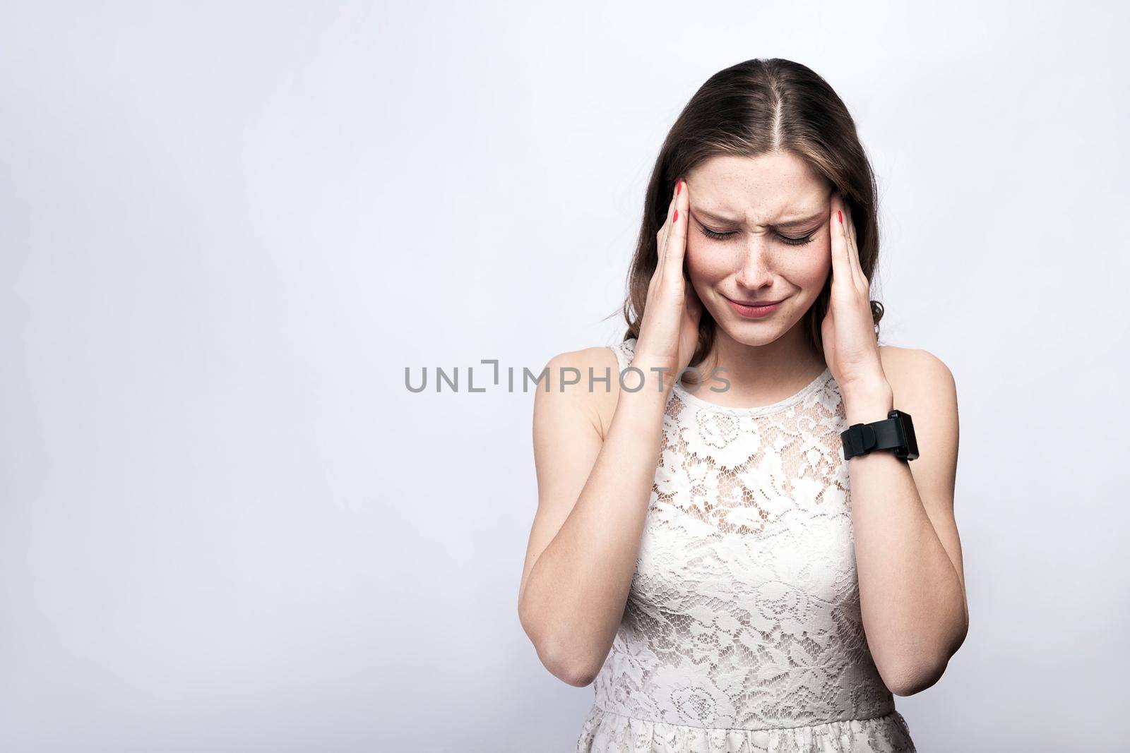 woman with freckles and white dress and smart watch with headache pain on silver gray background. by Khosro1