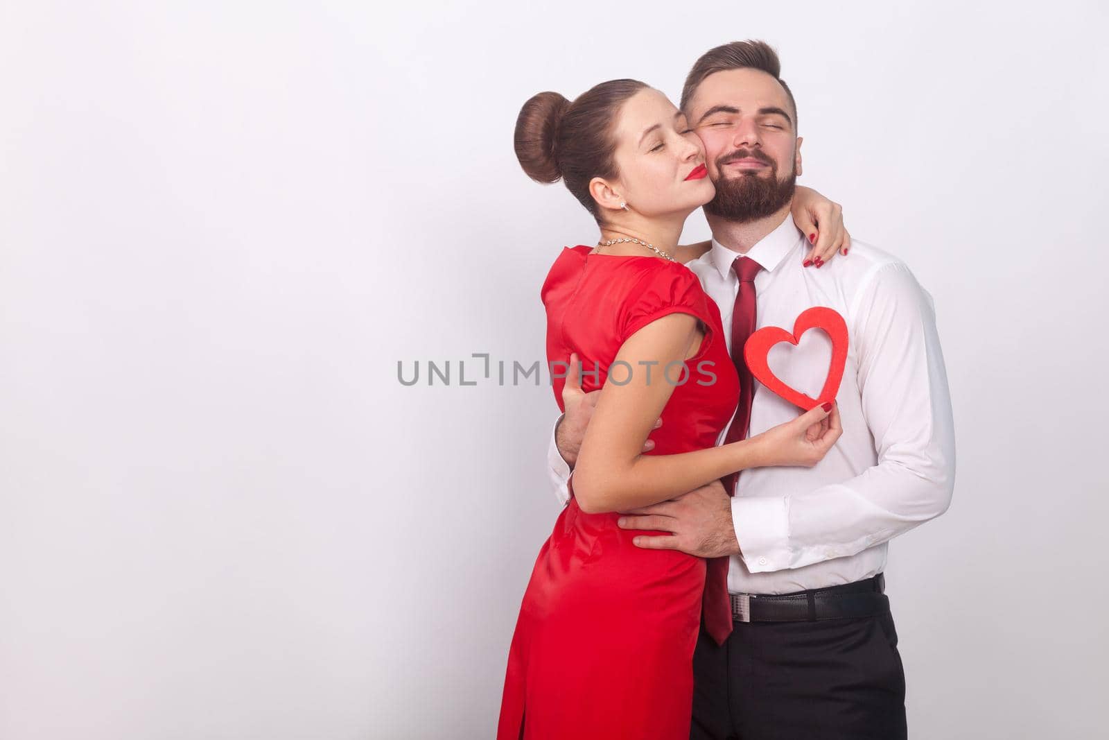 Young couple embrace with pleasure, closed eyes . Indoor, studio shot, isolated on gray background