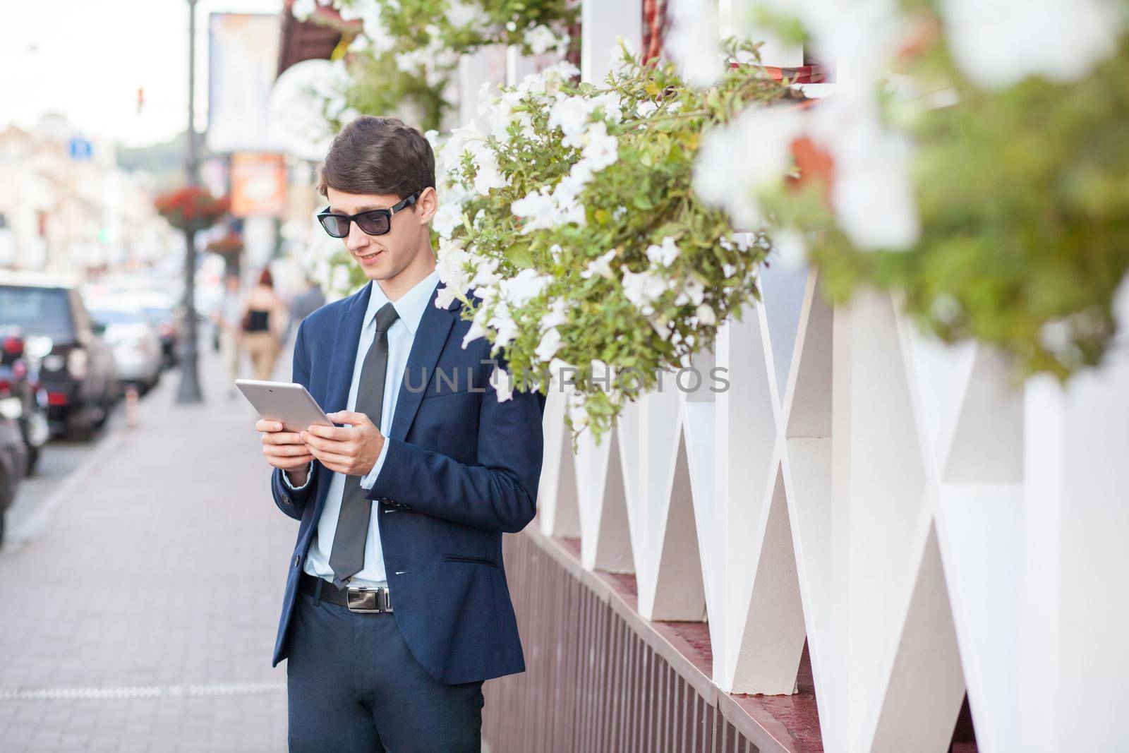 young man in business suit holding tablet on summertime day.