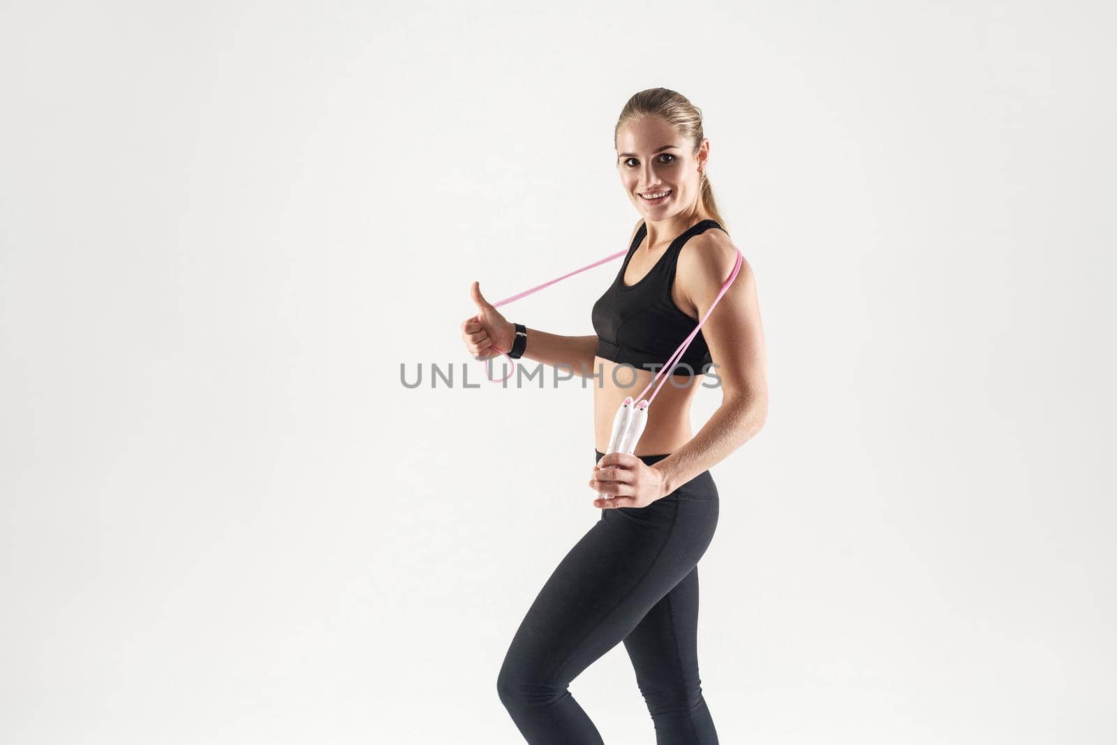 Young adult blonde girl holding a rope. The girl is engaged in fitness. Studio portrait of a girl for a healthy lifestyle.