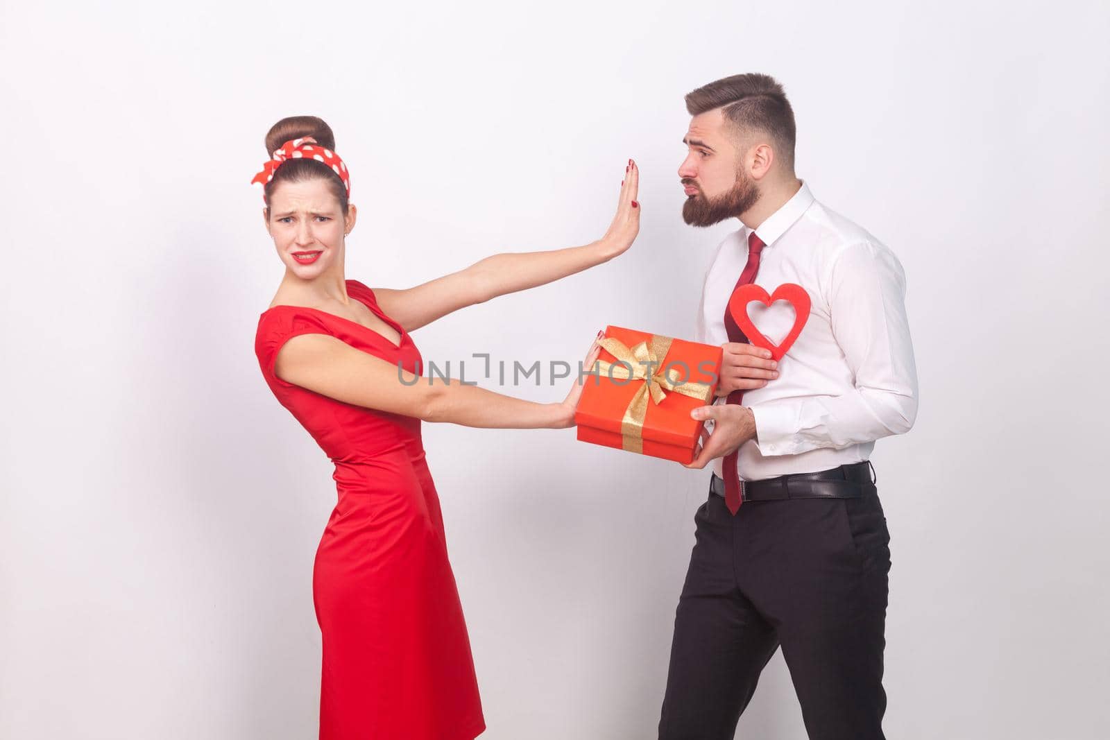 Woman in red dress, don't need present and love. Indoor, studio shot, isolated on gray background