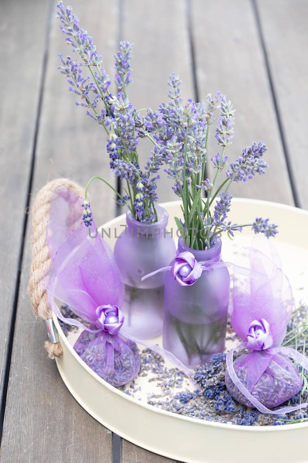 Lilac lavender in vases and lavender sachets in chiffon bags on a tray with dry flowers, aromatherapy, purple background, floral still life. High quality photo