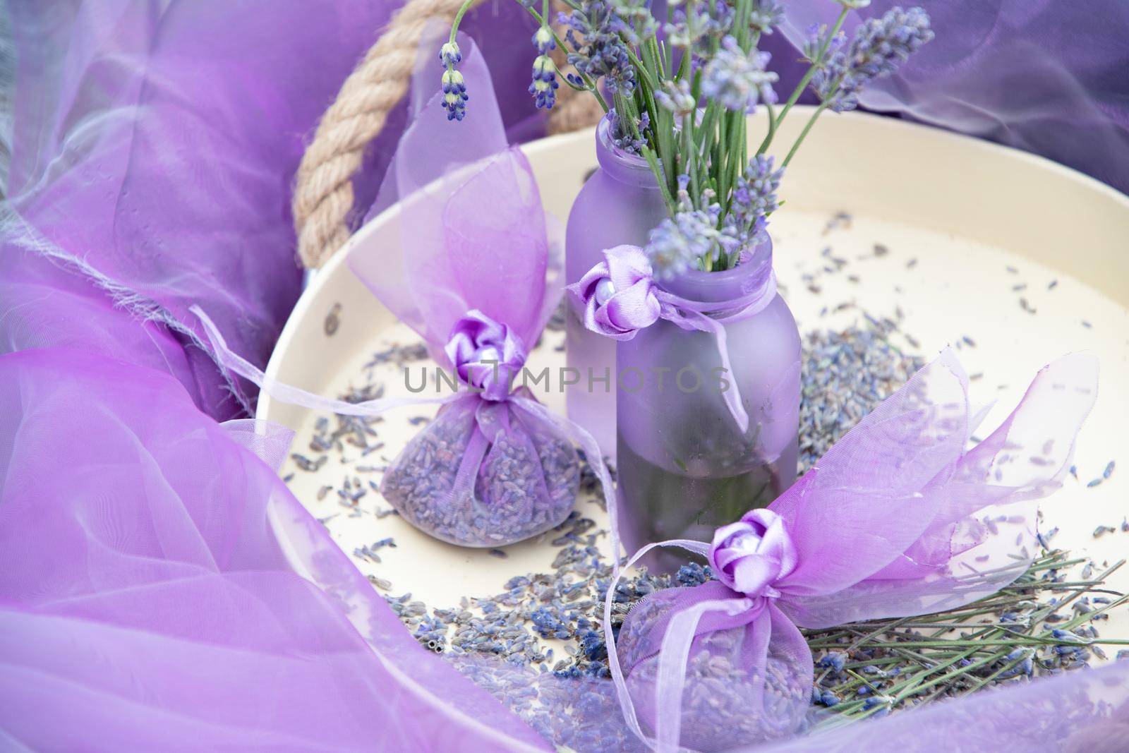 Lilac lavender in vases and lavender sachets in chiffon bags on a tray with dry flowers, aromatherapy, purple background, floral still life. High quality photo
