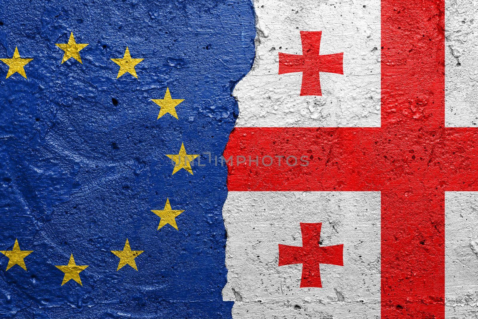 European Union and Georgia - Cracked concrete wall painted with a EU flag on the left and a Georgian flag on the right stock photo by adamr