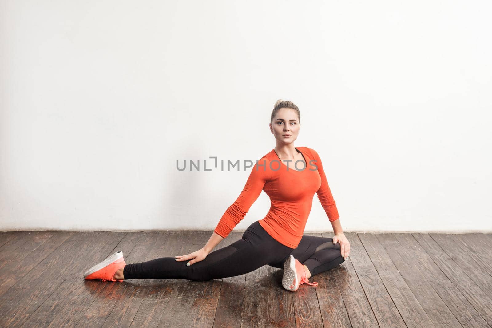 Cute woman looking at camera and doing stretching. Studio shot