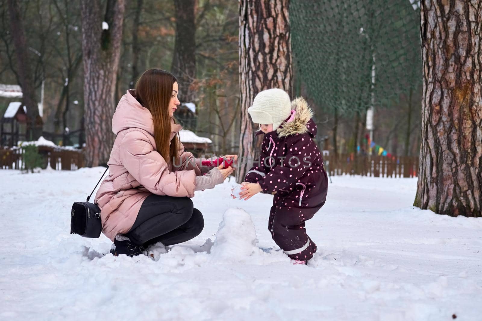 Caring mother puts gloves on her child on a winter day by jovani68