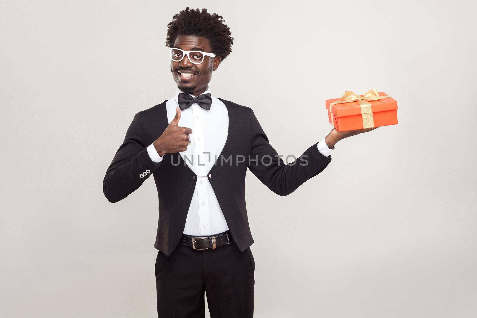 African man thumbs up and holding gift box. by Khosro1