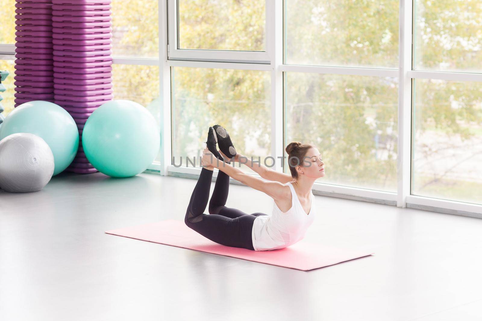 Woman doing yoga, bow posture, yoga. Dhanurāsana. Studio shot