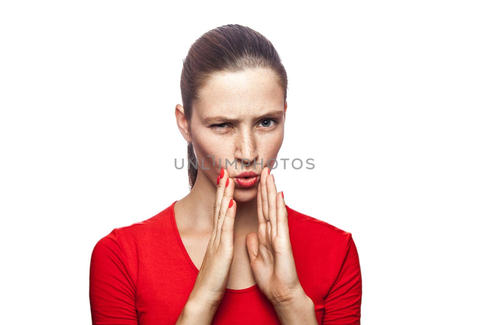 Portrait of serious woman in red t-shirt with freckles. looking at camera and telling secret, studio shot. isolated on white background.