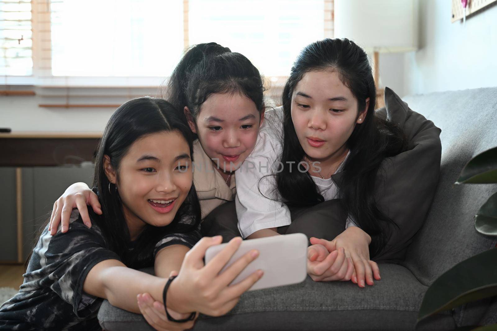 Happy Asian girls taking selfie with smart smartphone at home. by prathanchorruangsak