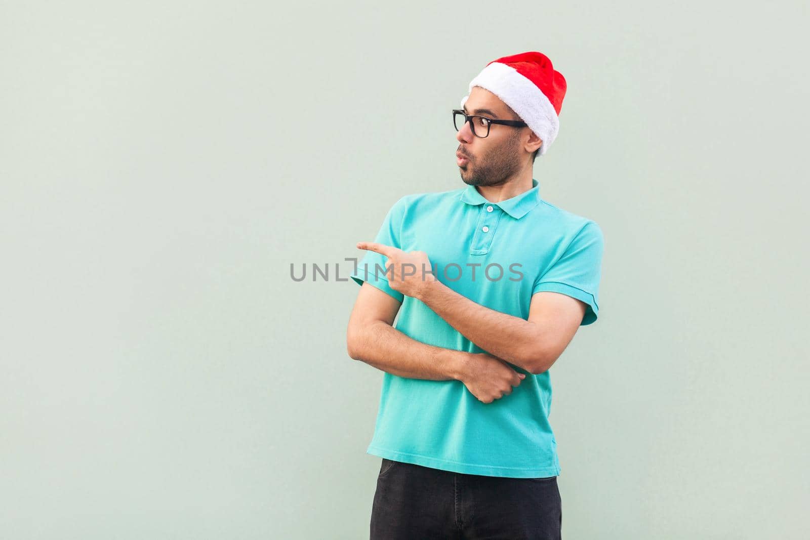 Wow! Handsome man with beard in shoked. Pointing away while standing isolated on gray background. Studio shot