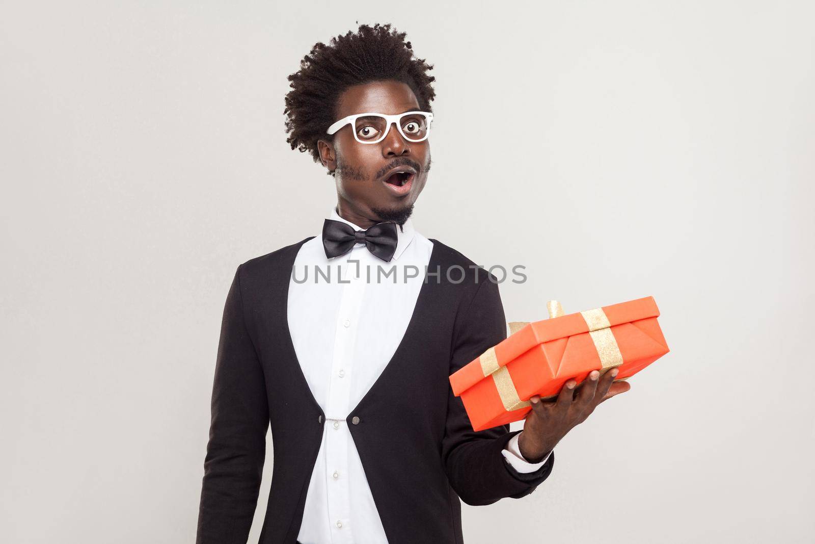 Amazement man holding gift box and shocked. Studio shot, gray background