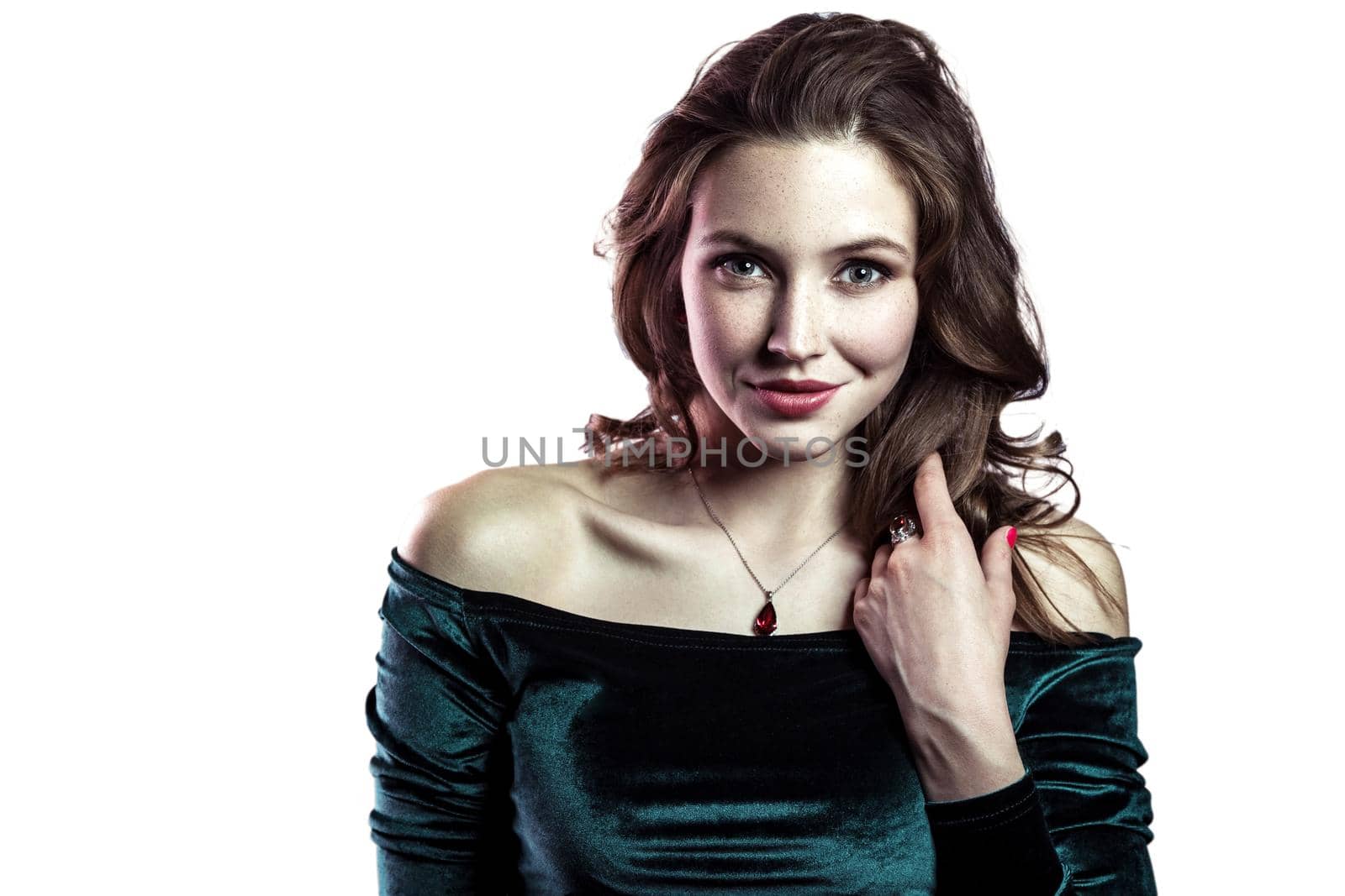 Portrait of beautiful sensual woman with makeup, hairstyle and natural freckles on her face in green dress posing and looking at camera with smile. indoor studio shot, isolated on white background.