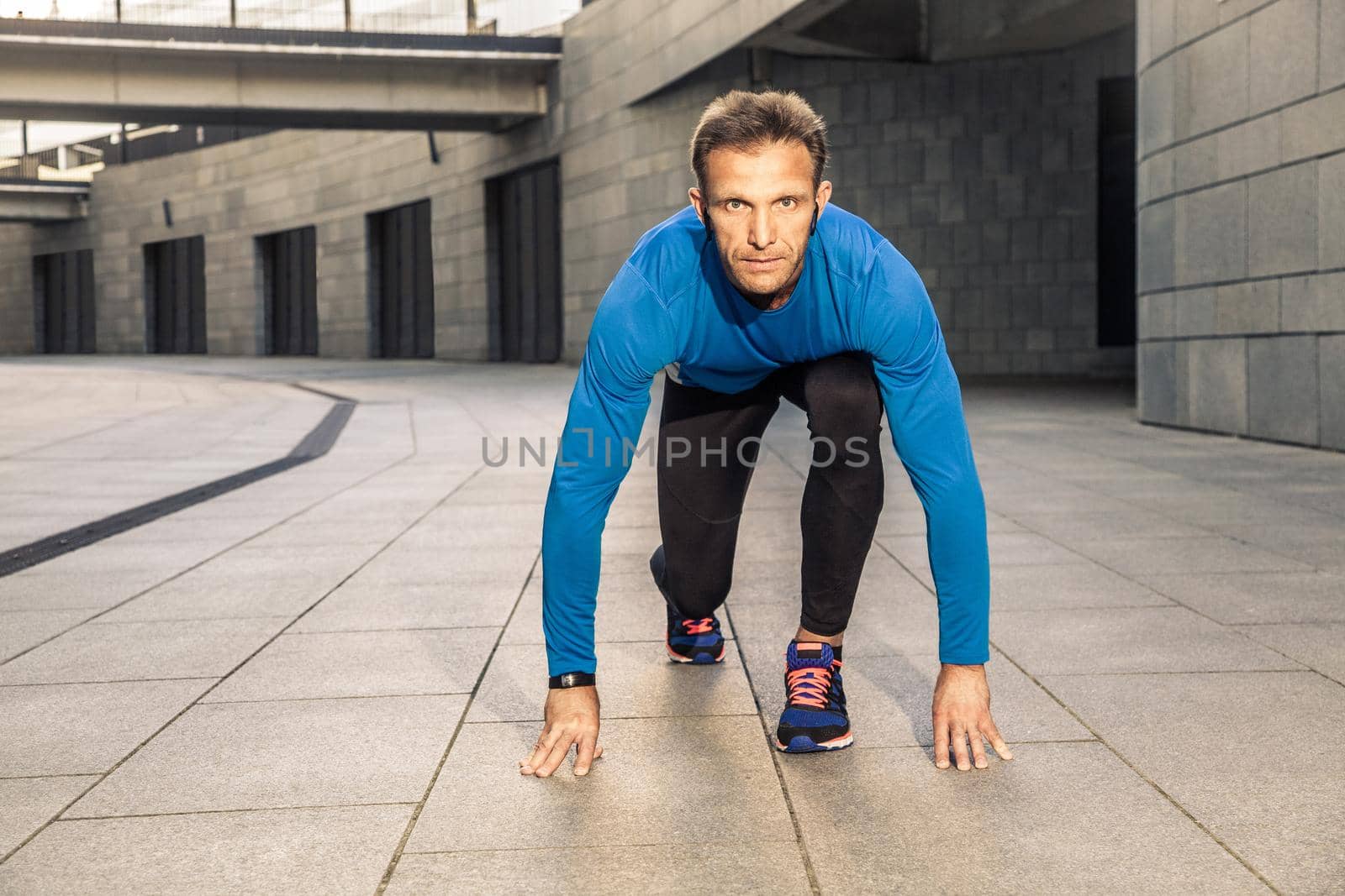 Handsome middle aged serious man in blue black sports uniform and headphones by Khosro1