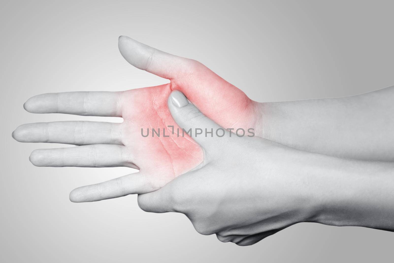 Closeup view of a young woman with pain on hand on gray background. Black and white photo with red dot.