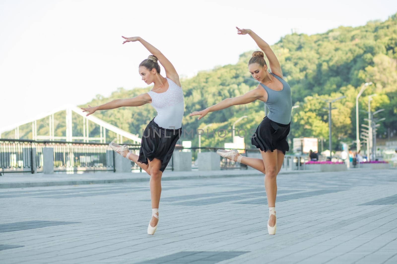 Two young beautiful twin sister dancing ballet in the city with ballet costume. urban sync dance. industrial street dancing. with special effect. synced posing. pointe ballet shoes and dress.