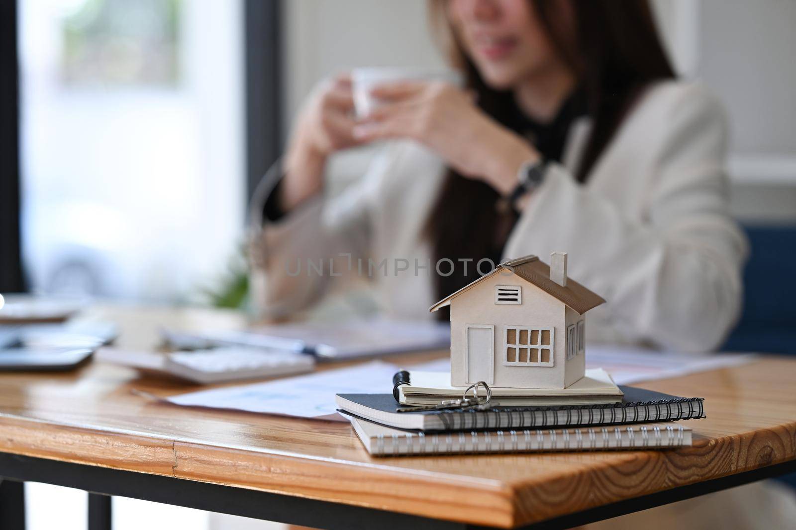 Small house model and keys on wooden table at real estate office . Real estate investment concept. by prathanchorruangsak