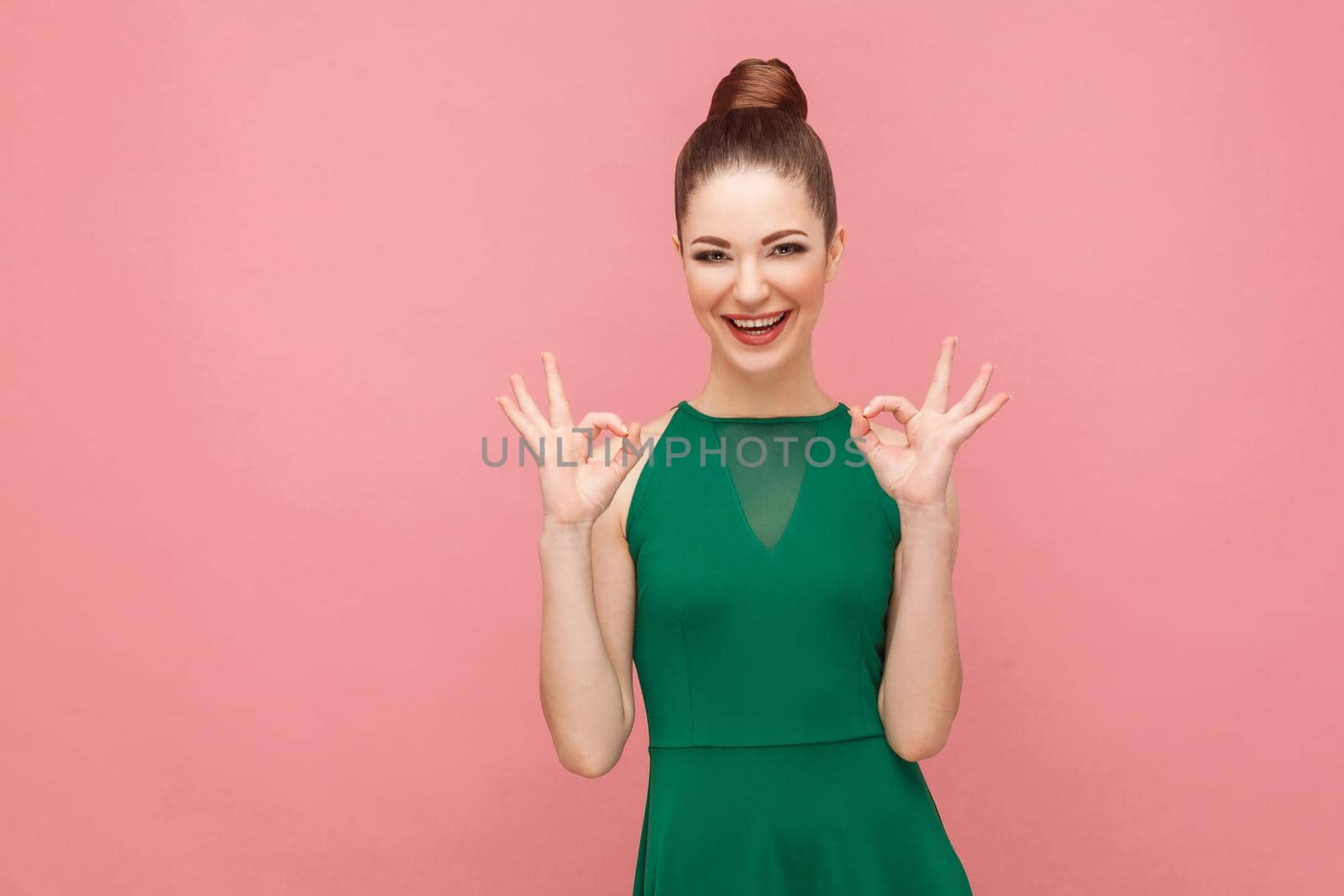 Attractive young adult woman showing ok sign. Expression emotion and feelings concept. Studio shot, isolated on pink background