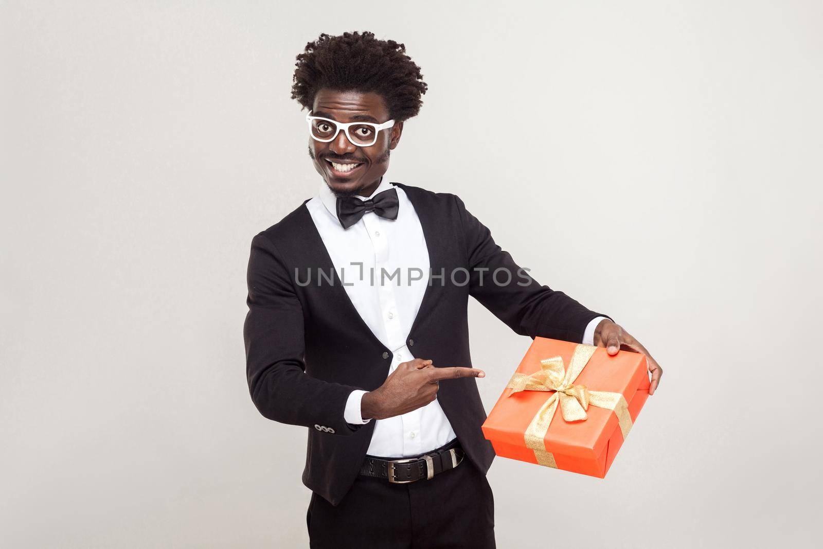 Valentine day. African businessman pointing fingers at gift box. Studio shot.