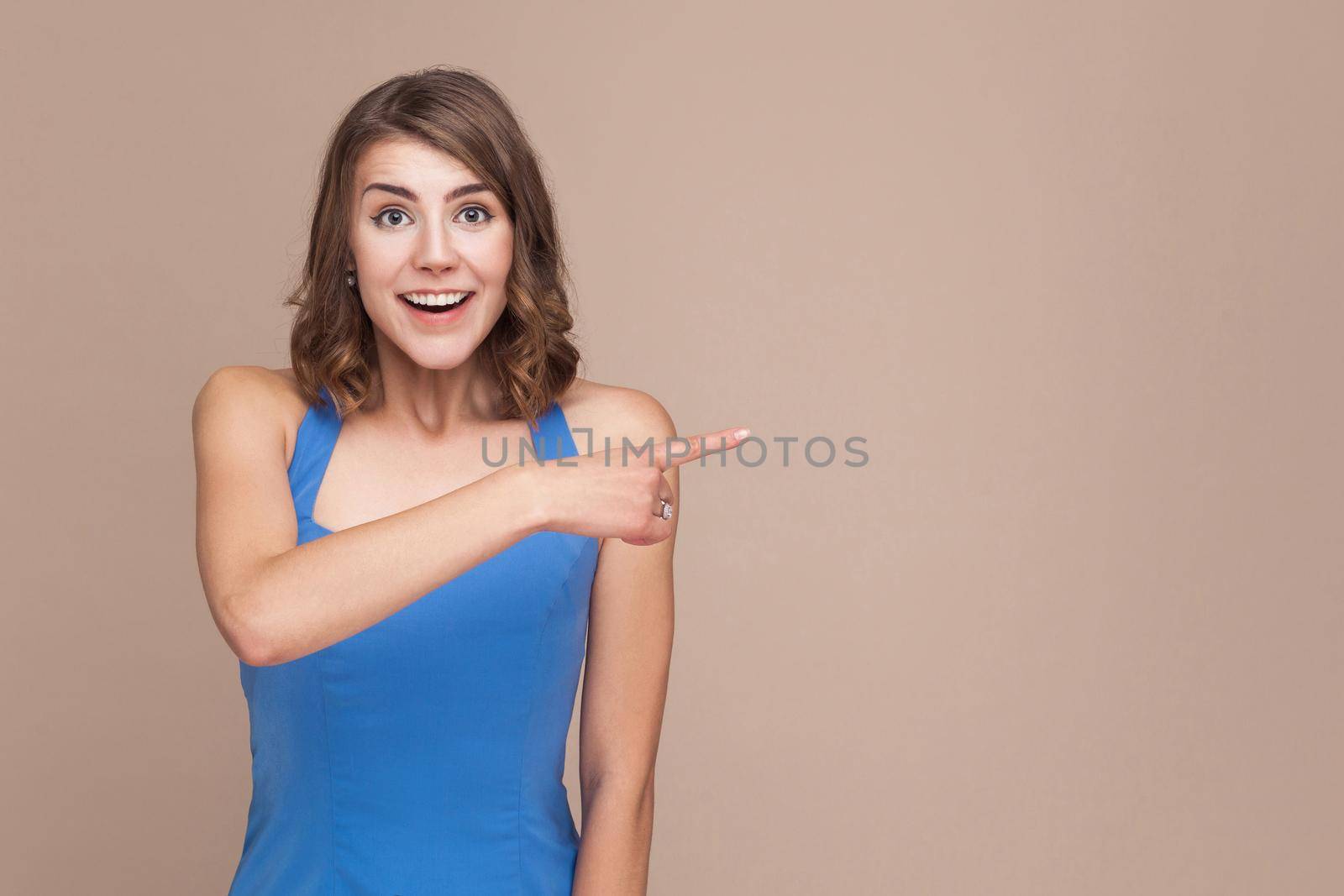 Amazement businesswoman pointing finger at copy space with shocked face. Studio shot