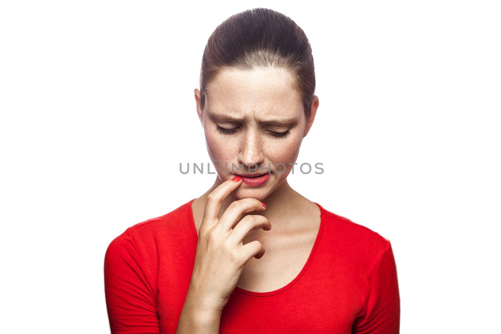 Portrait of thoughtful serious woman in red t-shirt with freckles, studio shot. isolated on white background.