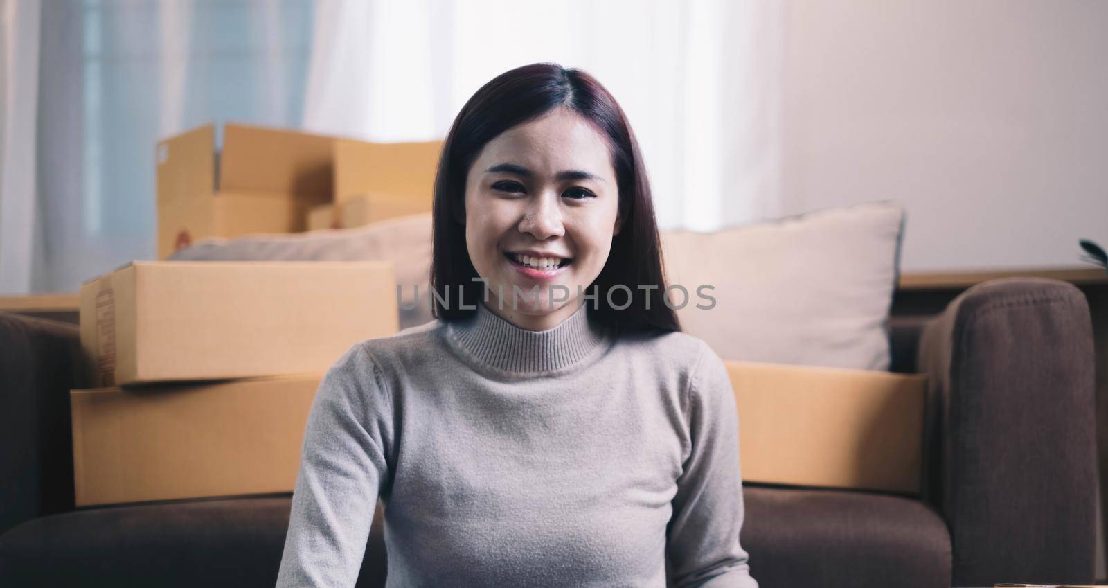 Portrait of Asian young woman SME working with a box at home the workplace.start-up small business owner, small business entrepreneur SME or freelance business online and delivery concept. by wichayada