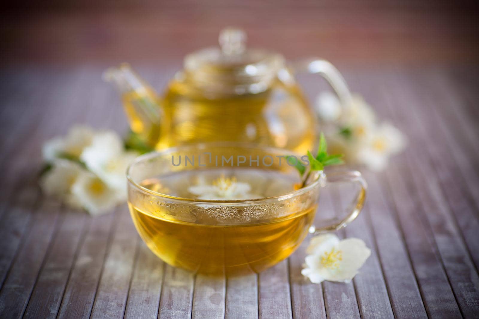 Composition with cup of jasmine tea and flowers on a bamboo background