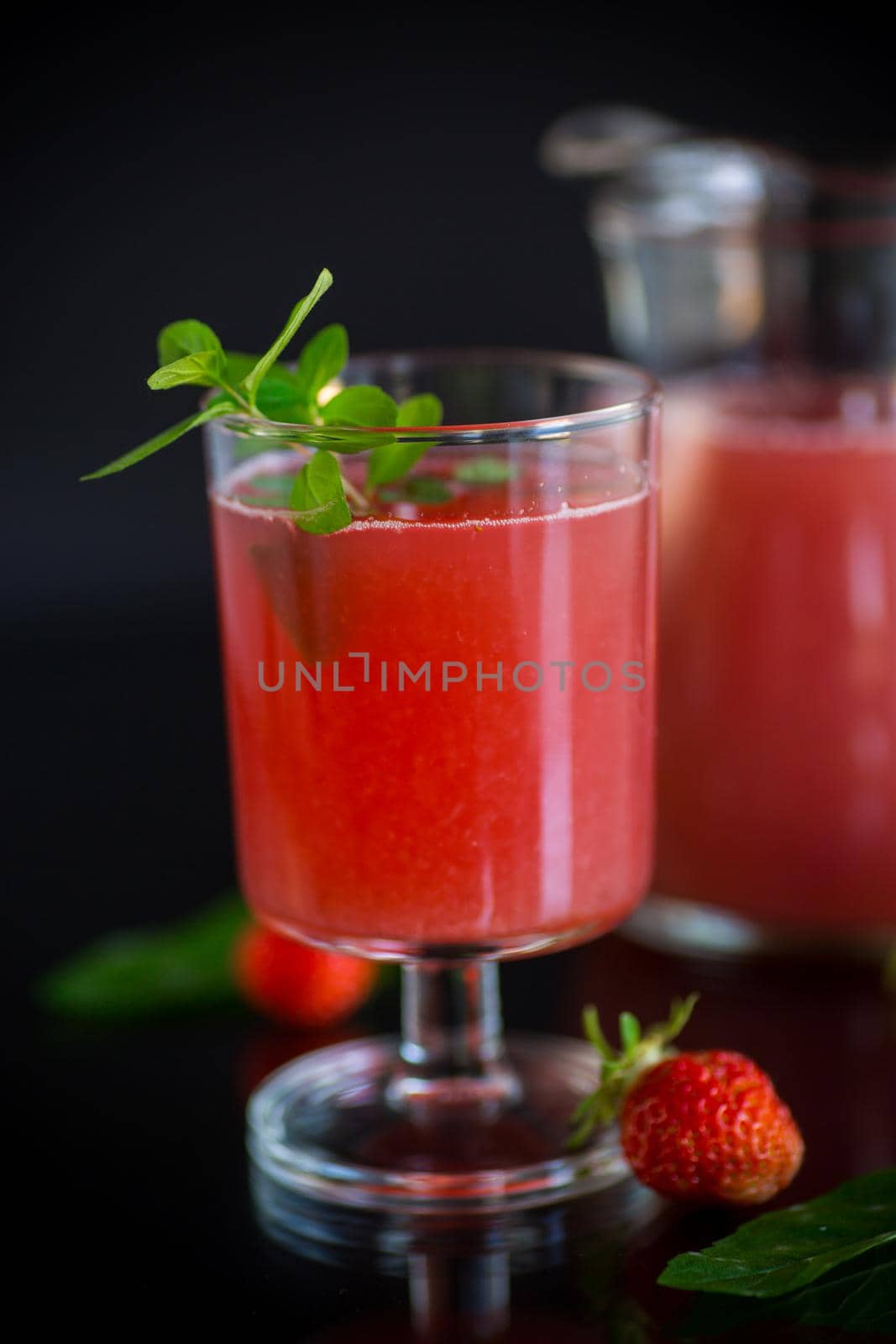 Cold summer strawberry kvass with mint in a glass isolated on black background