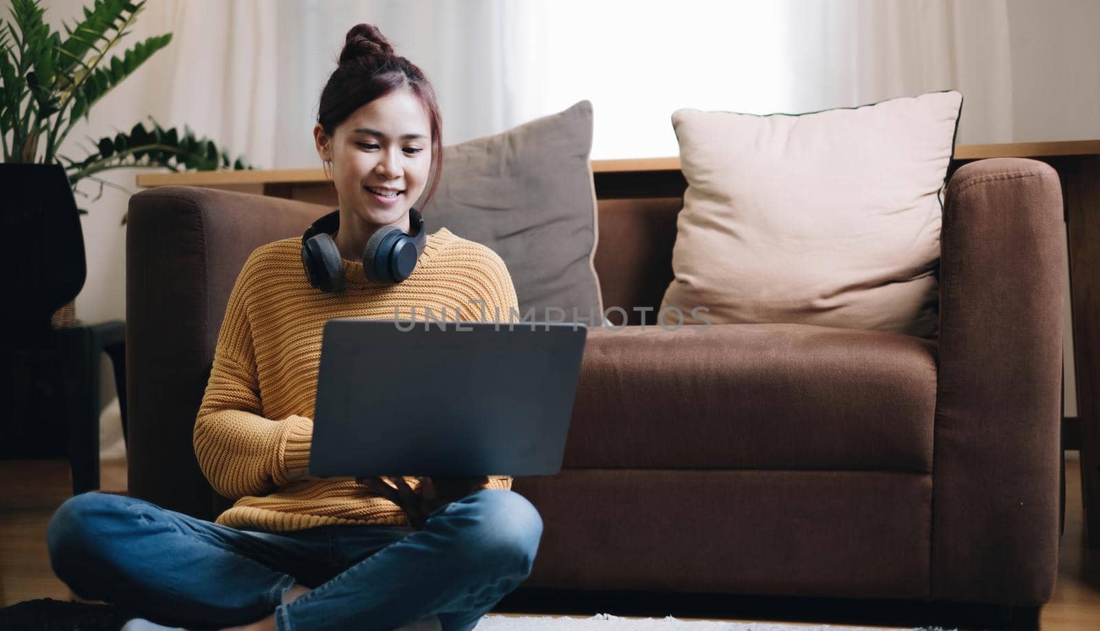 Shot of pretty young woman using her laptop while sitting on the floor at home. by wichayada