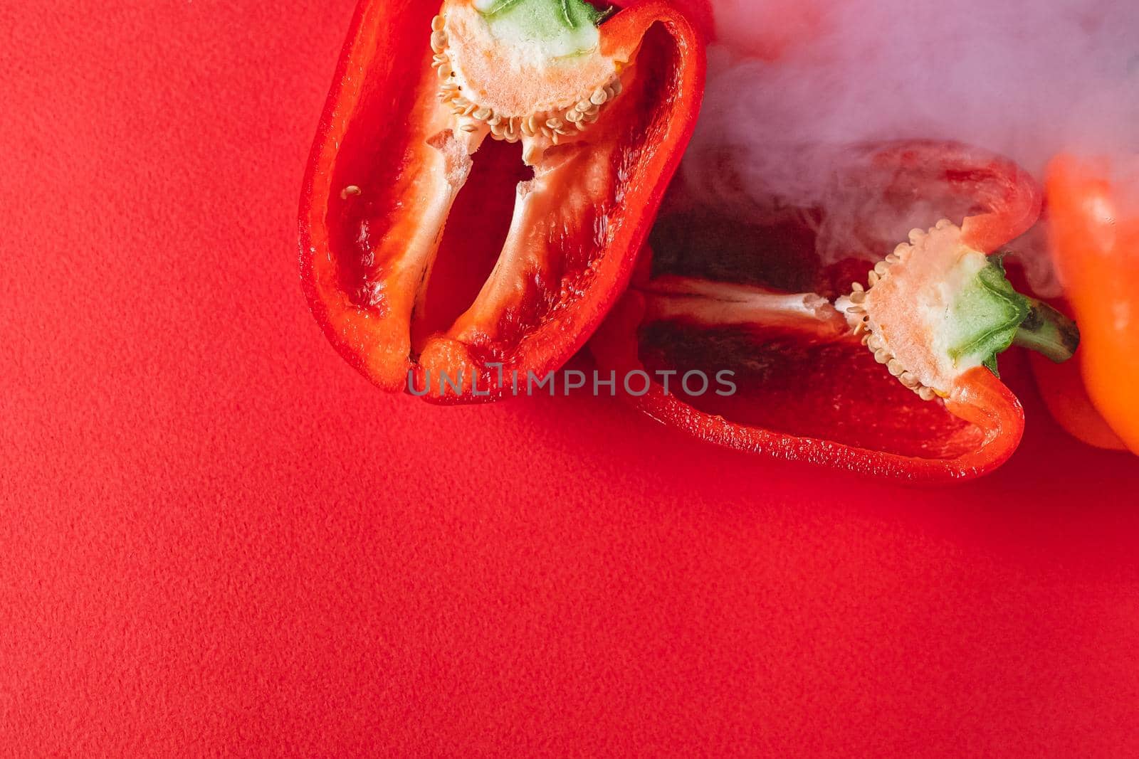 SWEET, fresh RED PEPPER ON A RED BACKGROUND, cut in half, thick smoke around. proper nutrition. fresh vegetables