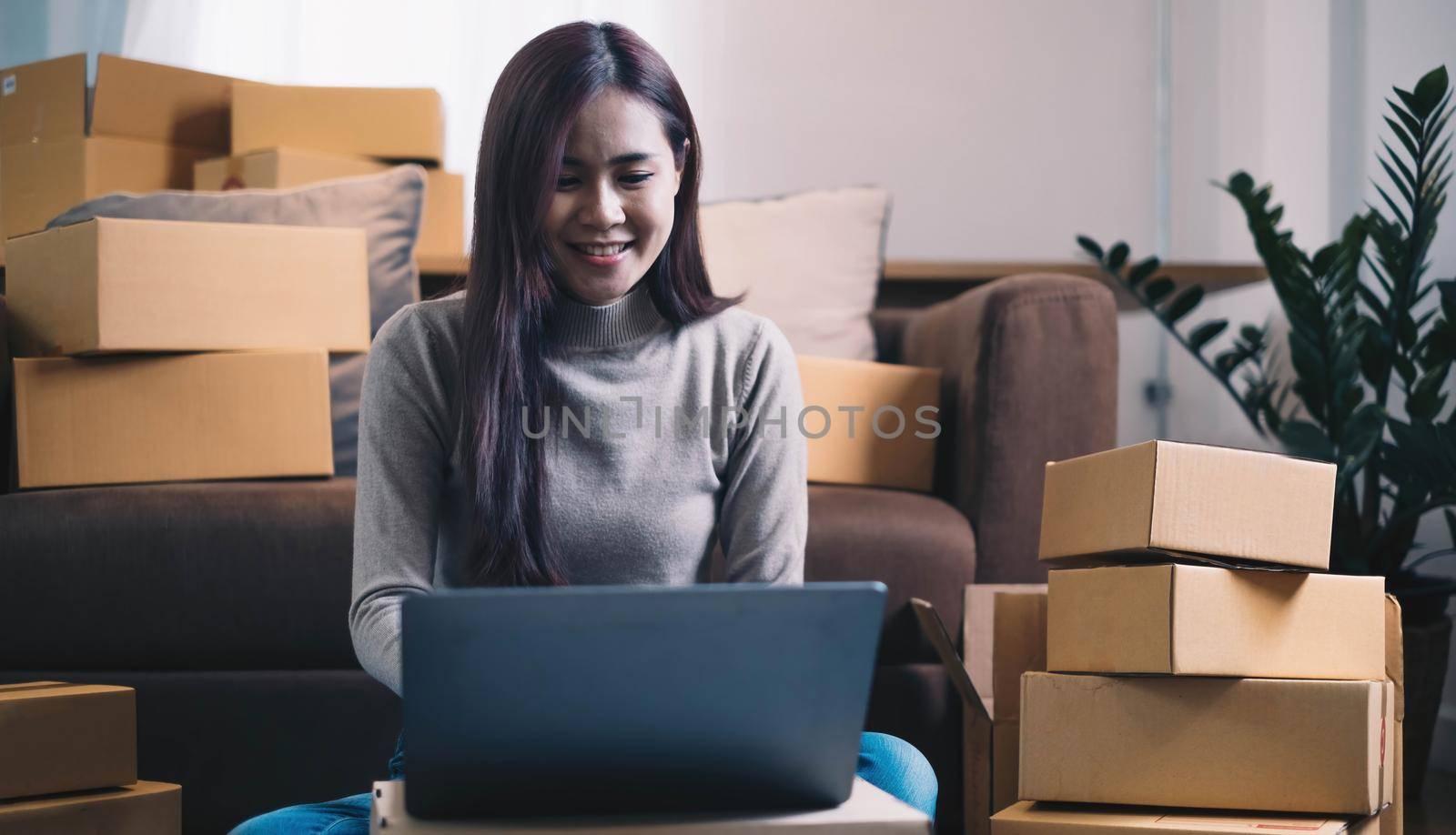 Startup small business entrepreneur or freelance Asian woman using a laptop with box, Young success Asian woman with her hand lift up, online marketing packaging box and delivery, SME concept. by wichayada