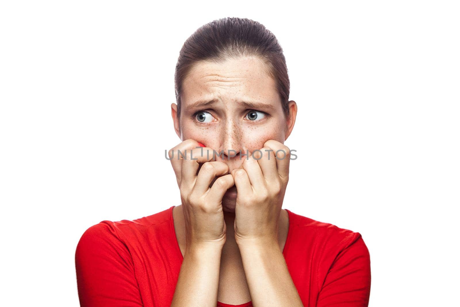 Portrait of worried scared woman in red t-shirt with freckles. looking at camera, studio shot. isolated on white background.