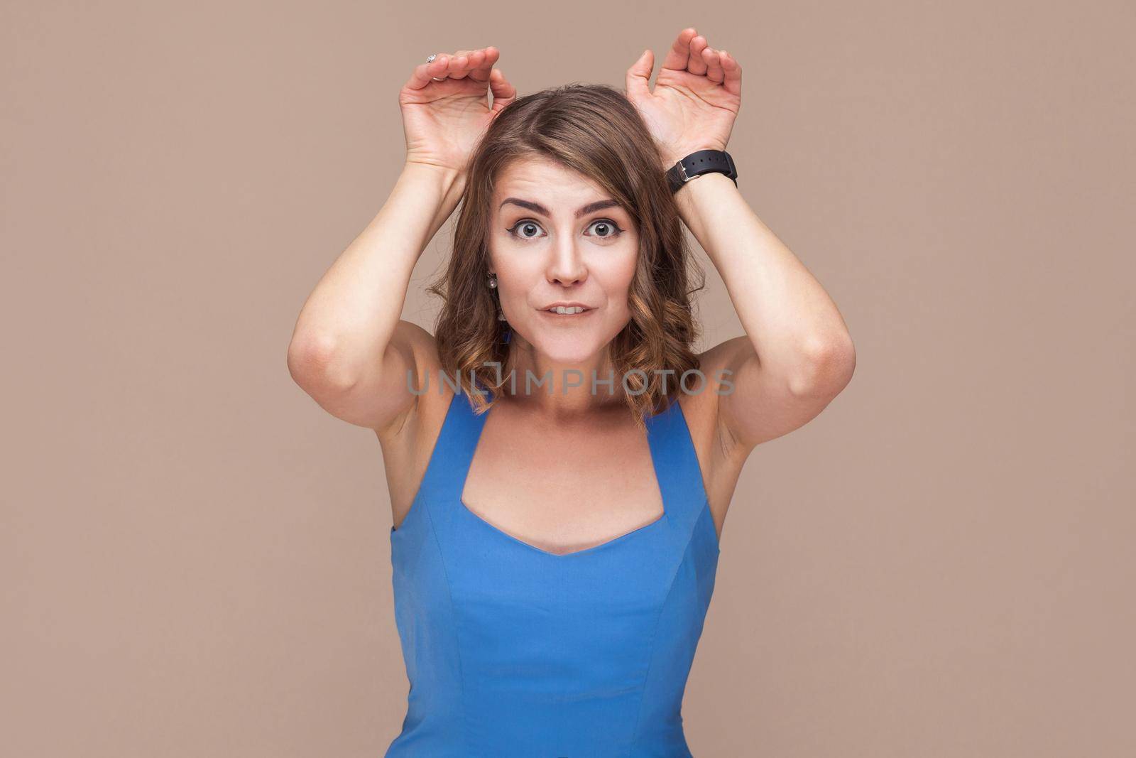Comic woman showing rabbit sign at camera. Studio shot