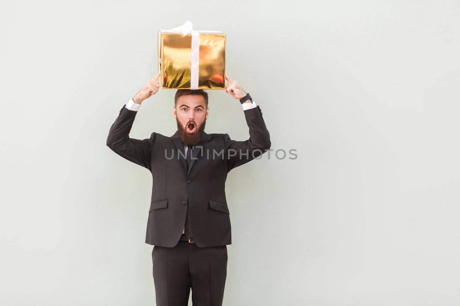 The box balances on the head a amazed businessman. Studio shot